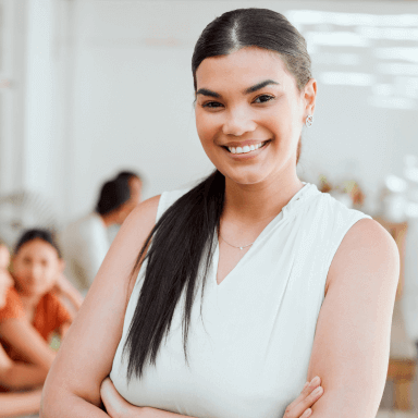 Smiling woman in white blouse with colleagues in background, modern office setting, diverse group, teamwork concept.